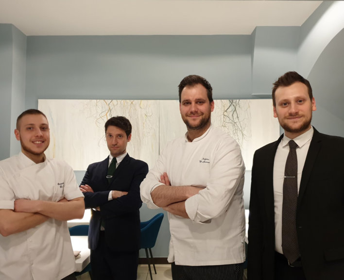 Quatre chefs et sommeliers réunis dans la salle d'un restaurant