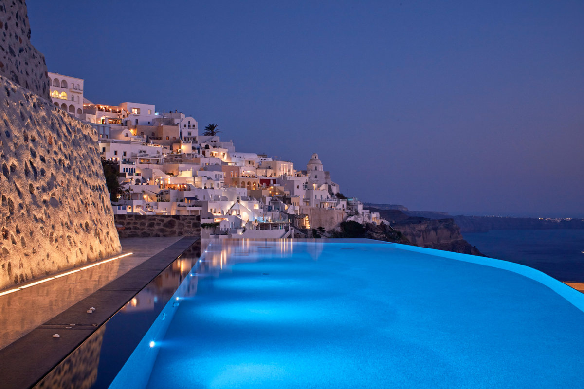 Piscine à débordement avec vue mer et colline avec maison en chaut blanche