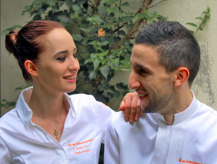Deux chefs, une femme à gauche et un homme à droite en veste de cuisinier blanche brodée orange