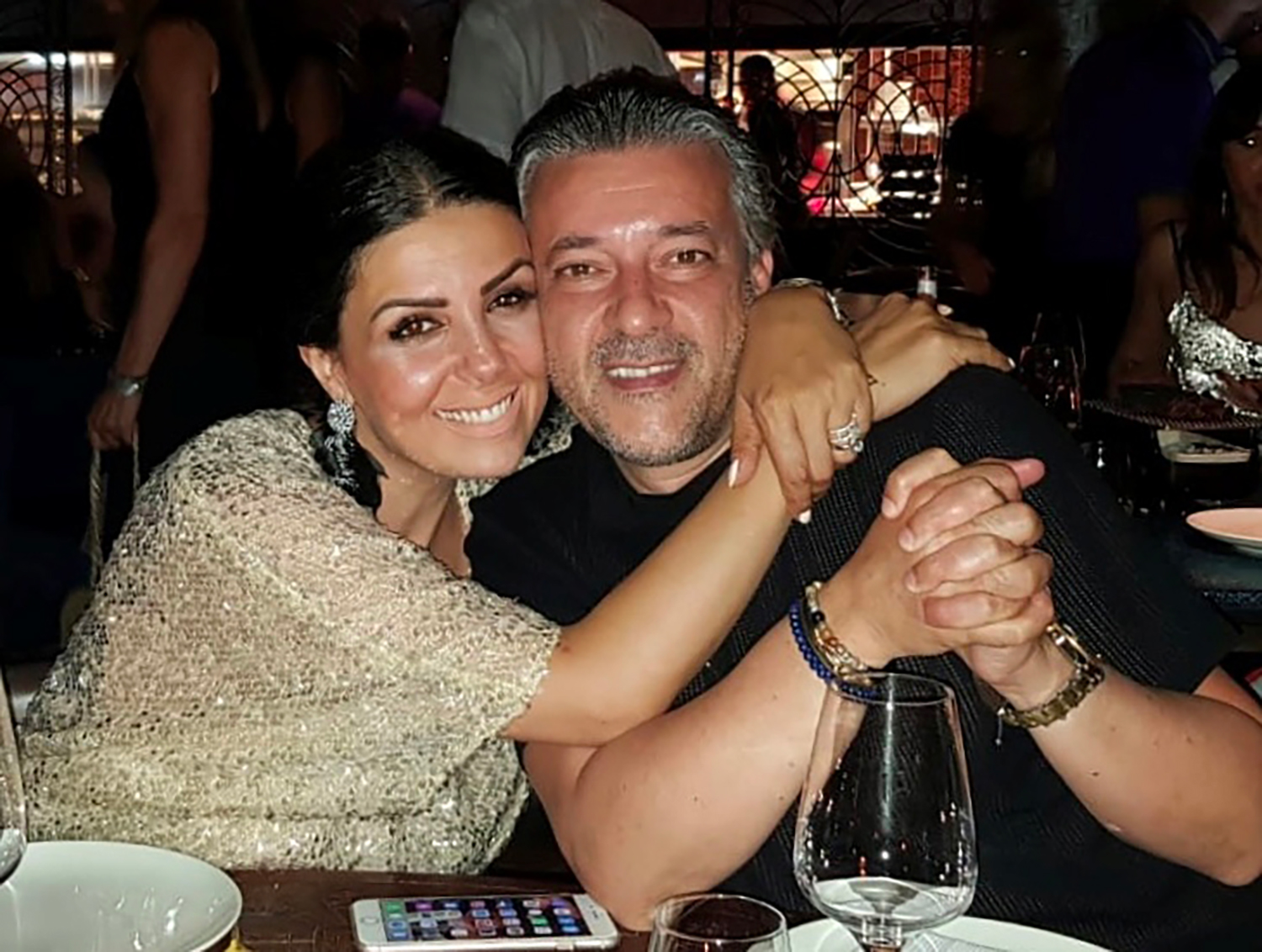 Une femme et un homme dans les bras l'un de l'autre sur attablés à une table de restaurant avec verre à vin