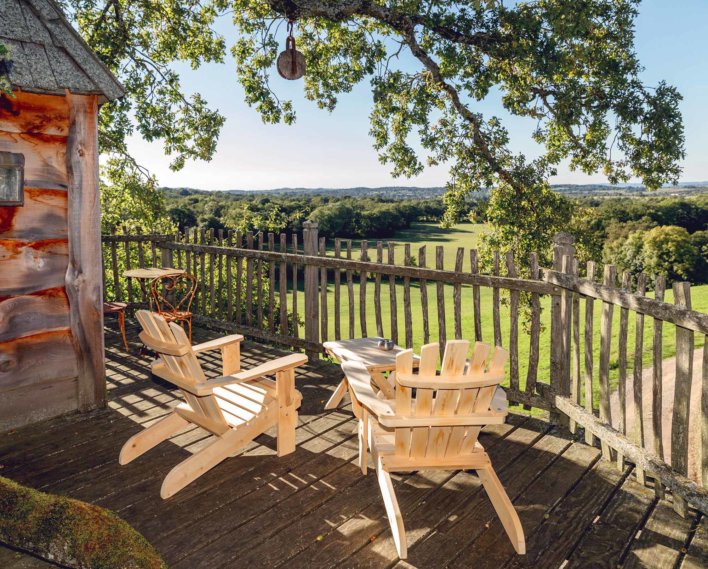 Balcon perché dans une cabane dans les bois avec vue sur la clairière