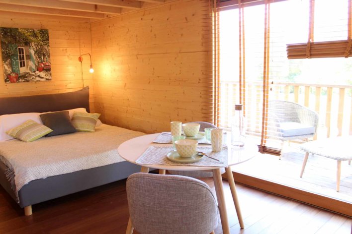 Intérieur d'une cabane en bois avec lit double et table ronde dressée pour un petit-déjeuner