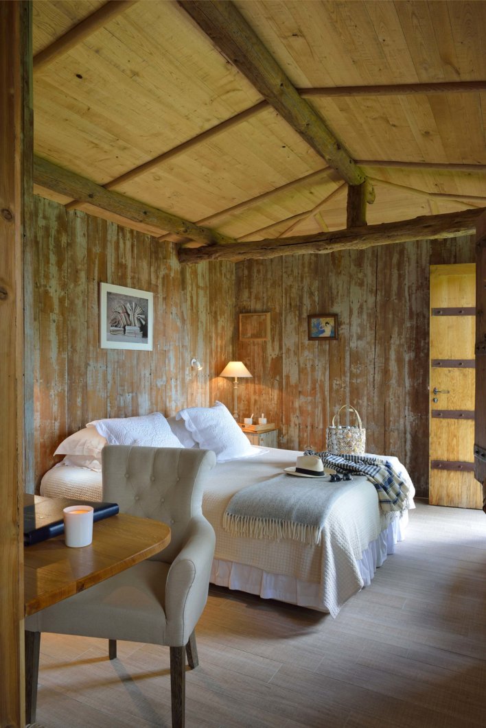 Chambre toute en bois avec lit double et fauteuil capitonné gris