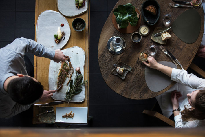 Vue aérienne sur un serveur qui découpe un poisson et une femme qui tient un verre de vin blanc attendant de se faire servir