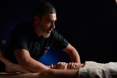 Un homme praticien réalise un massage d'une cuisse