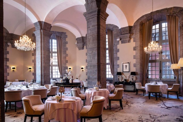 Salle de restaurant avec grande hauteur sous plafond et tout en voûte de pierres blanches