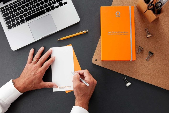 Coffret cadeau posé sur un bureau de travail à coter d'une personne qui est en train d'écrire un mort sur la carte du coffret cadeau