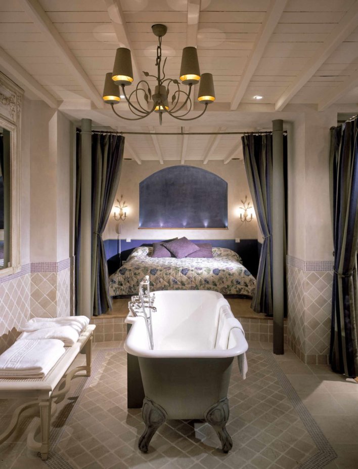 Photo de la chambre avec la baignoire au premier plan et le lit au second plan