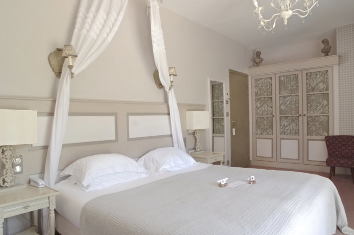 Chambre spacieuse avec une décoration de couleurs blanc et beige assez épurée avec lit double