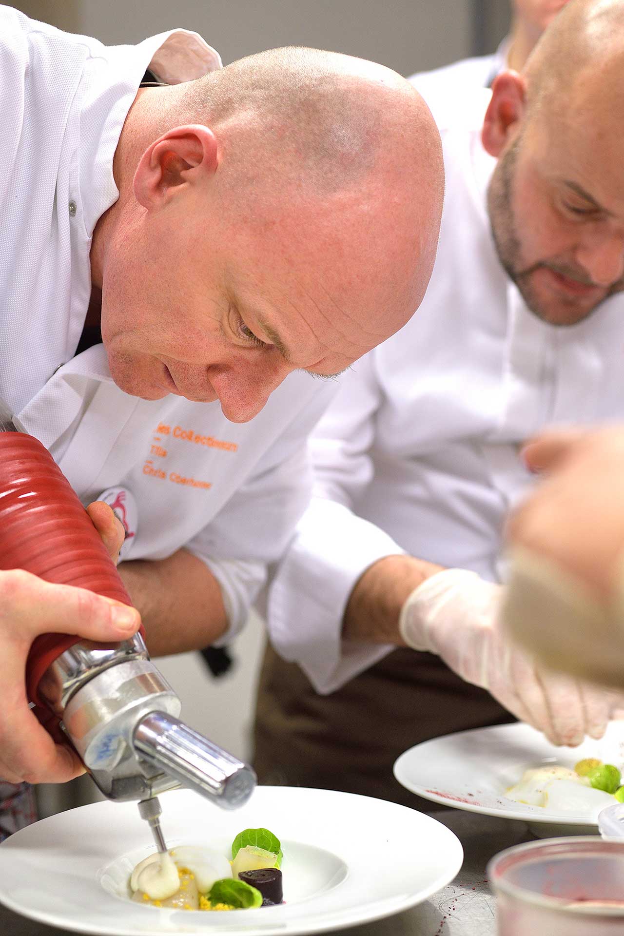Deux chefs en cuisine prépare nue assiette à l'aide d'un siphon