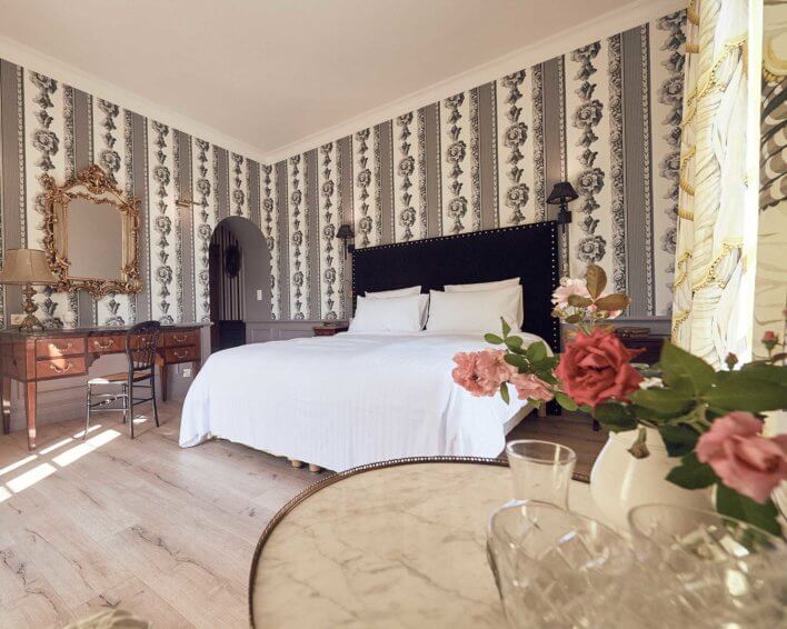 Chambre double avec lit en linge blanc, tapis au papier peint à motif, mobilier en bois anciens