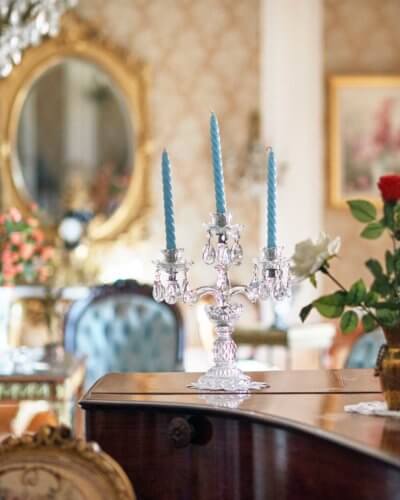 Photo de détail sur le plateau d'un piano à queue, bougeoir et bougies bleu, quelques éléments de décor en arrière plan