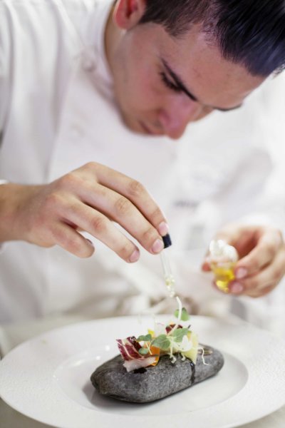 Un chef dépose une gouttte d'huile à l'aide d'une pipette sur un plat
