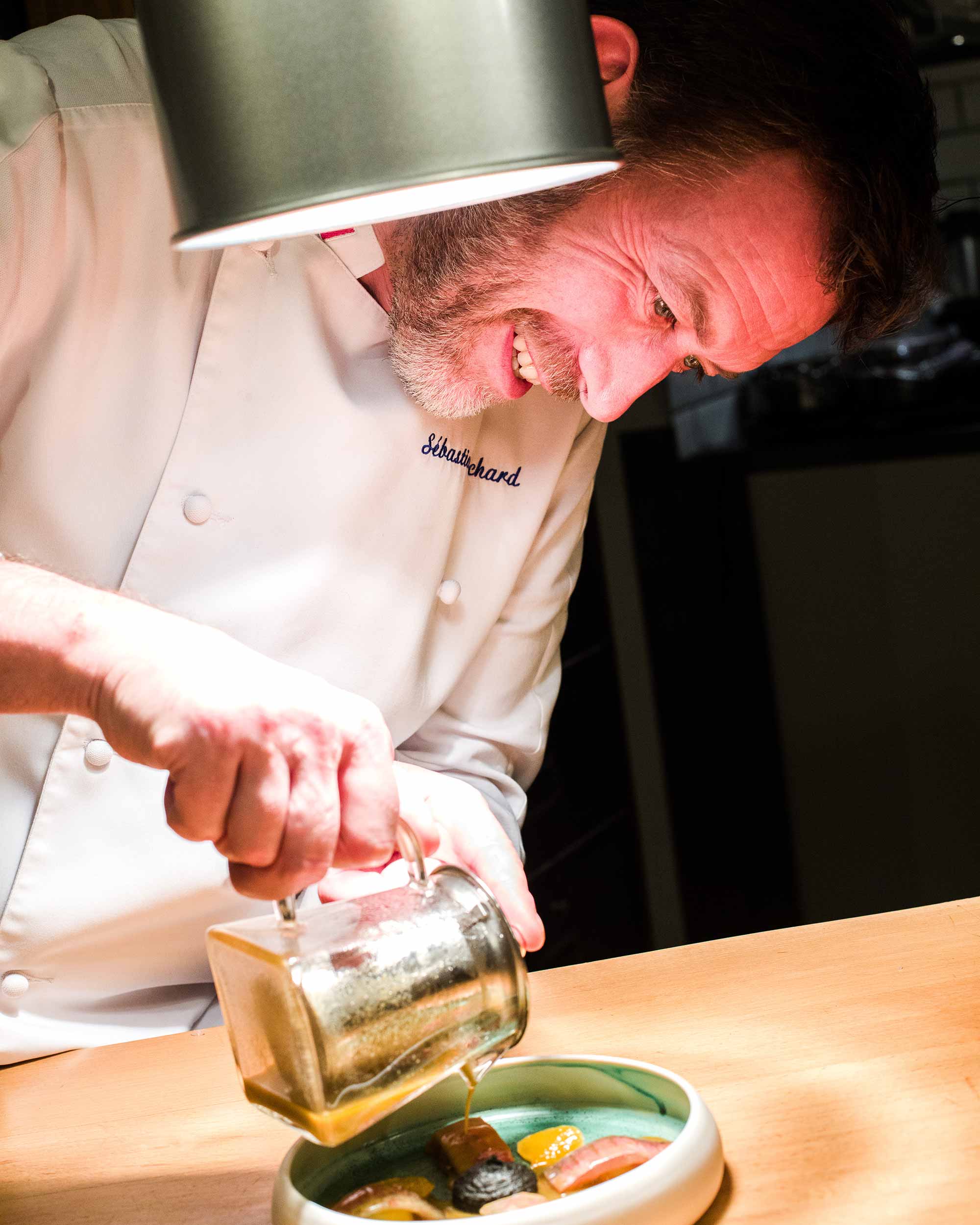 Chef en train de verser un jus vert dans une assiette