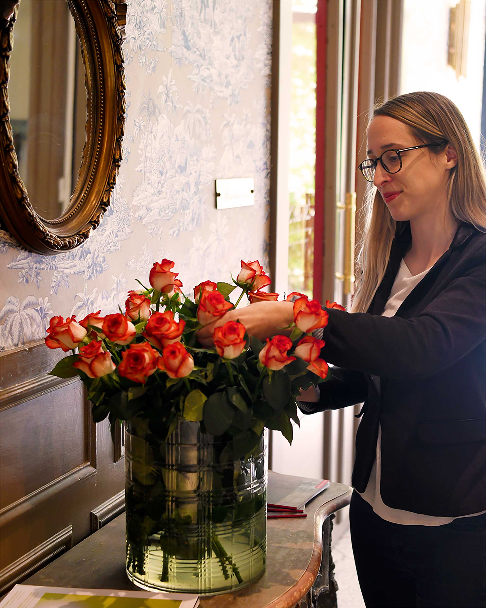 Femme en blazer bleu marin, elle arrange un bouquet de rose