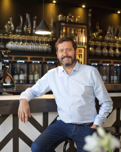 Photo portrait d'un homme sur un tabouret, devant un bar à vin