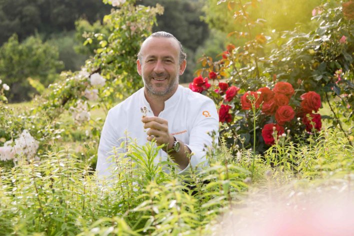 Chef dans un potager avec une fleur à la main